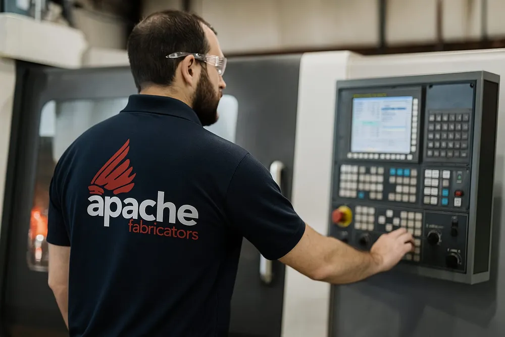 Apache Fabricators machinist at a CNC control panel in the Houston shop